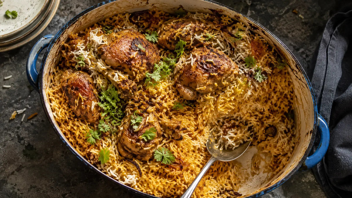 Classic chicken biryani with golden basmati rice and fried onions in a well-used blue enamel casserole.