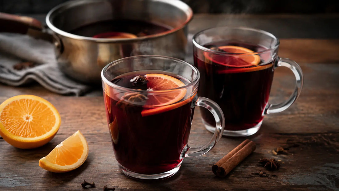 Classic homemade mulled red wine served steaming in clear glass mugs with orange and warming winter spices.