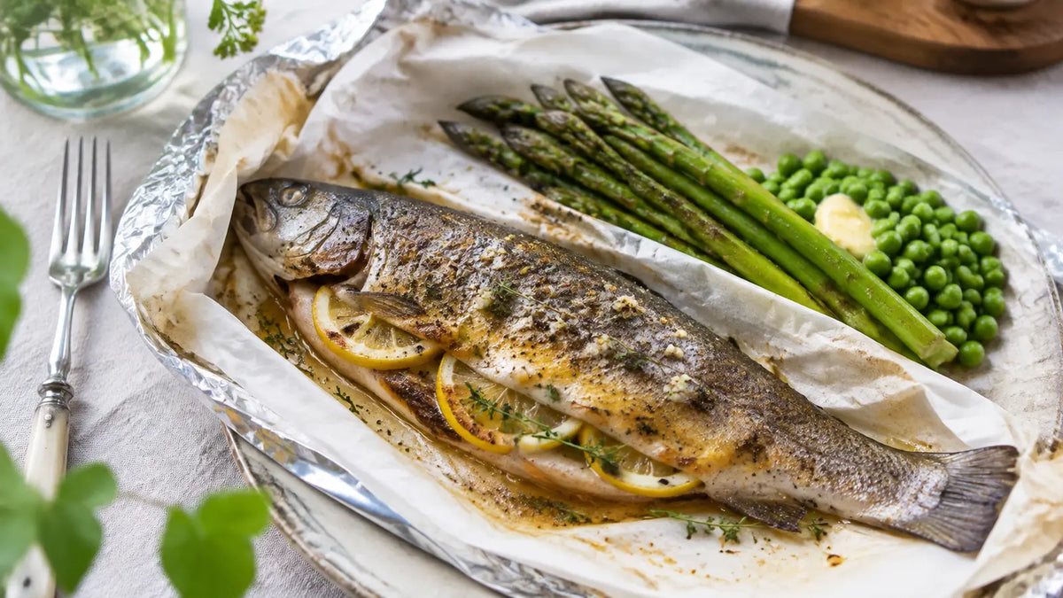 Whole foil-baked lemon pepper trout filled with lemon and herbs and served with asparagus and buttered peas.