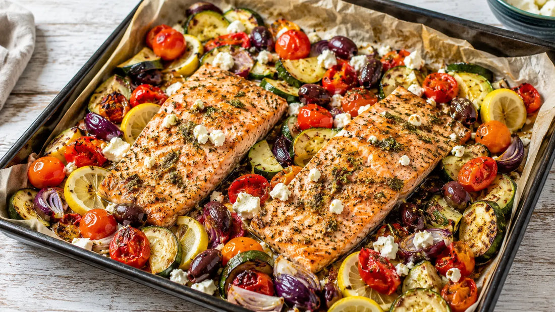 Greek-seasoned baked salmon traybake with courgette, cherry tomatoes, red onion, olives, lemon and feta.