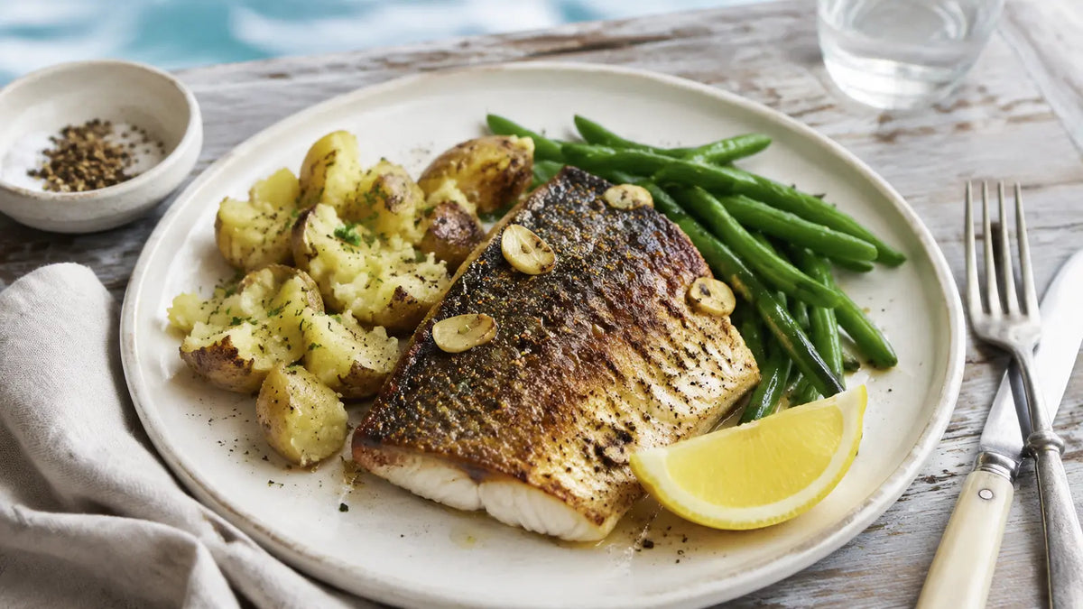 Pan-seared lemon pepper and garlic sea bass served with crushed new potatoes, green beans and a fresh lemon wedge.