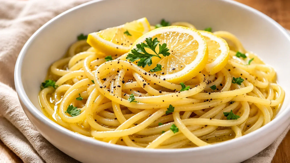 Lemon Pepper Pasta served in a white bowl with fresh lemon slices, parsley and cracked black pepper.