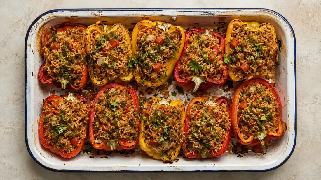 Moroccan Baharat spiced rice stuffed red and yellow peppers roasted in an enamel baking dish.