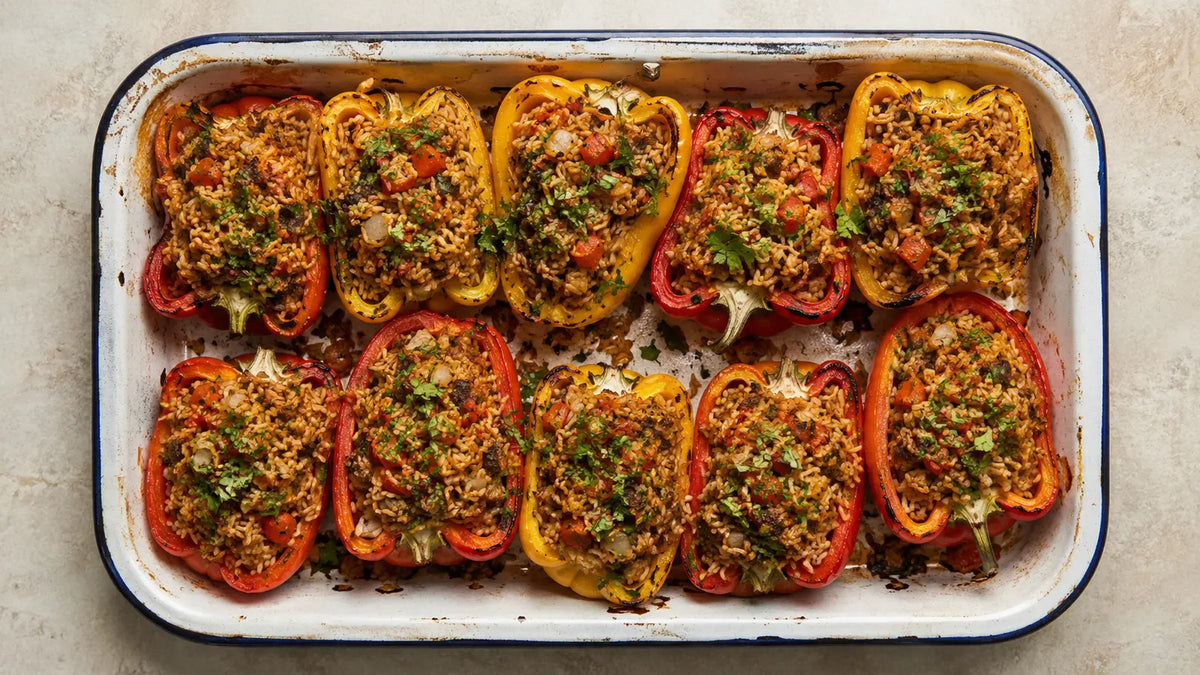 Moroccan Baharat spiced rice stuffed red and yellow peppers roasted in an enamel baking dish.