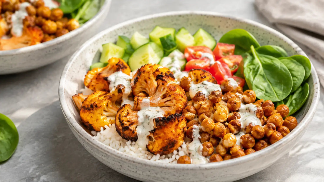 Roasted cauliflower and chickpea tikka bowls with rice, cucumber, tomatoes, spinach and yoghurt drizzle.